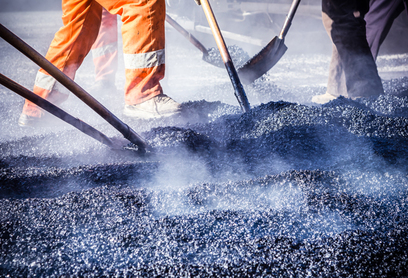 Workers making asphalt with shovels at road constructio